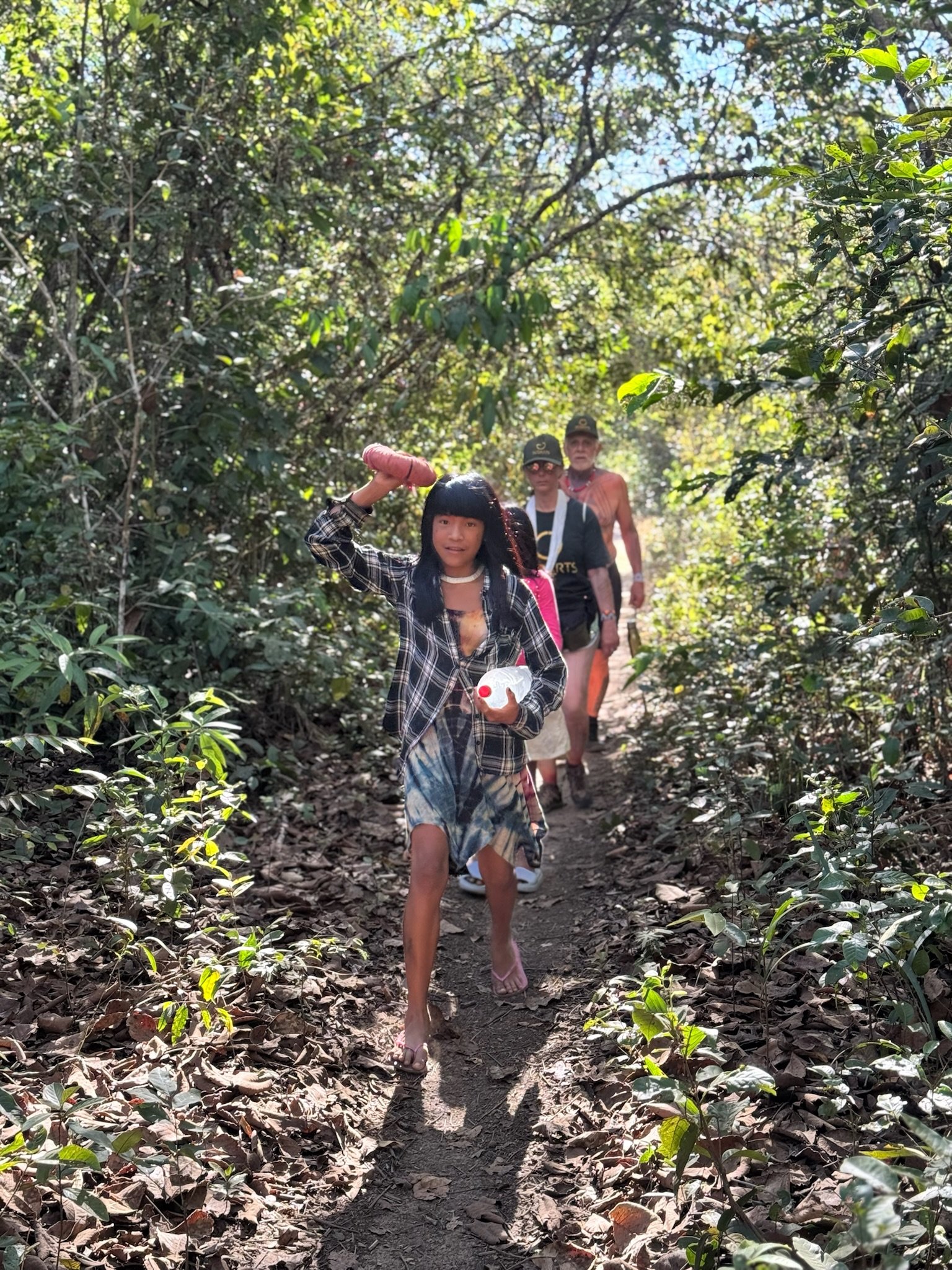 Grupo caminhando na mata, incluindo crianças