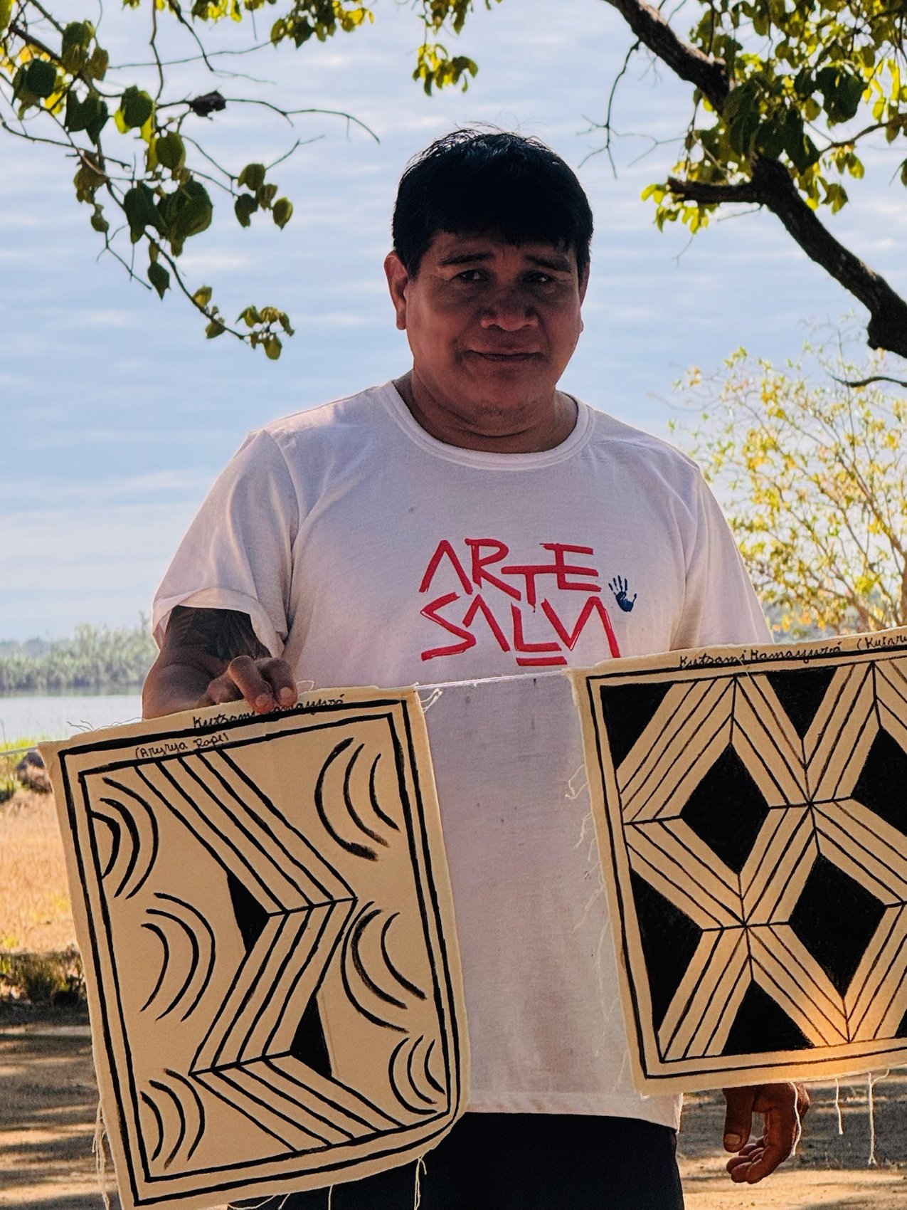Liderança Kamayurá com painel de grafismo, camiseta Arte Salva